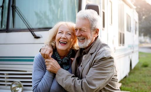 An older couple hugging outside their RV